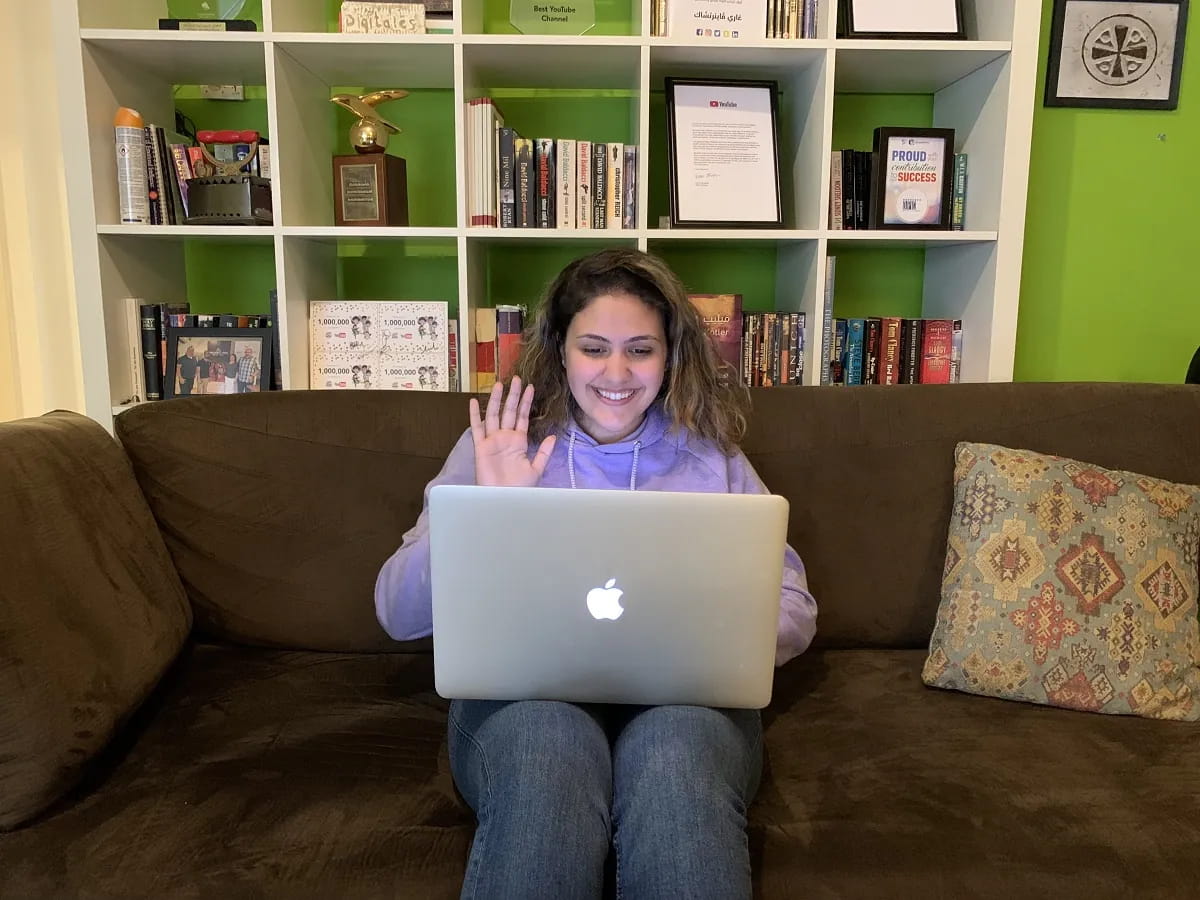 A team member waving hello from a sofa with a laptop, in the studio.