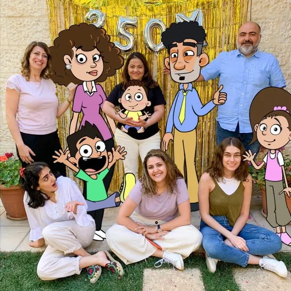 The team in a garden, celebrating with cut-outs of the Our Family Life characters.