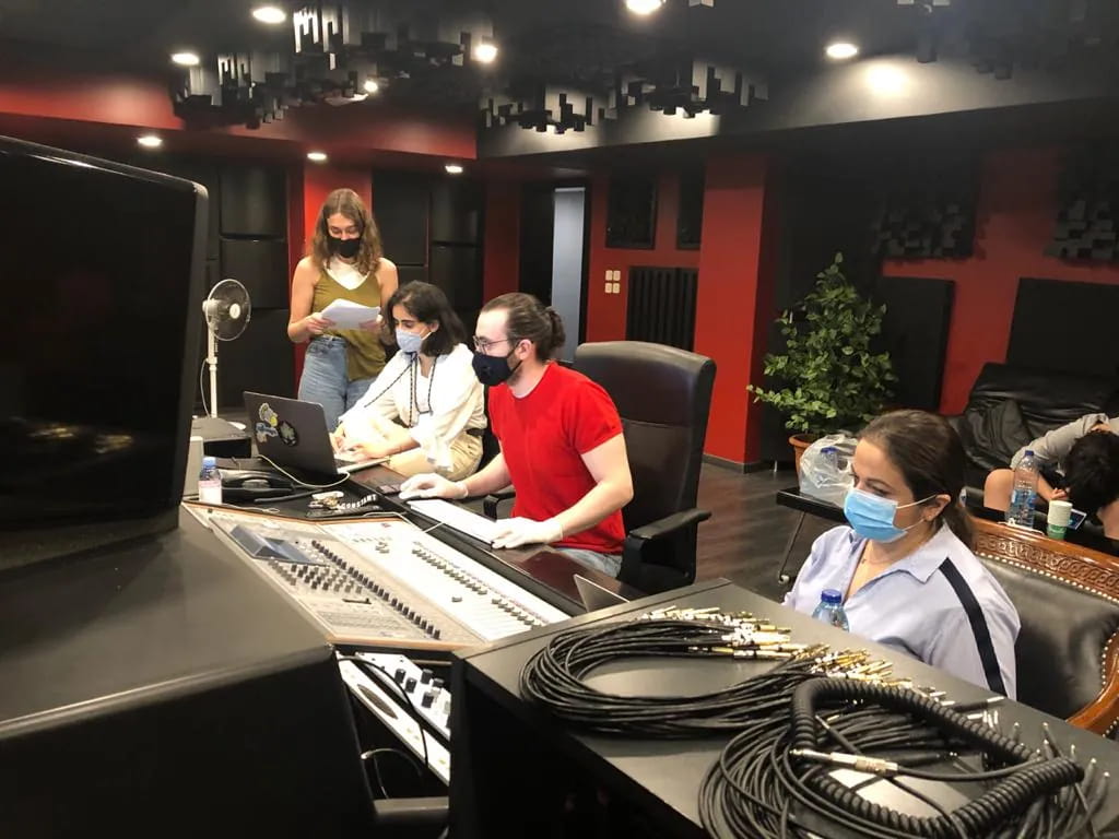 Three team members in face masks at a mixing console, recording a session.