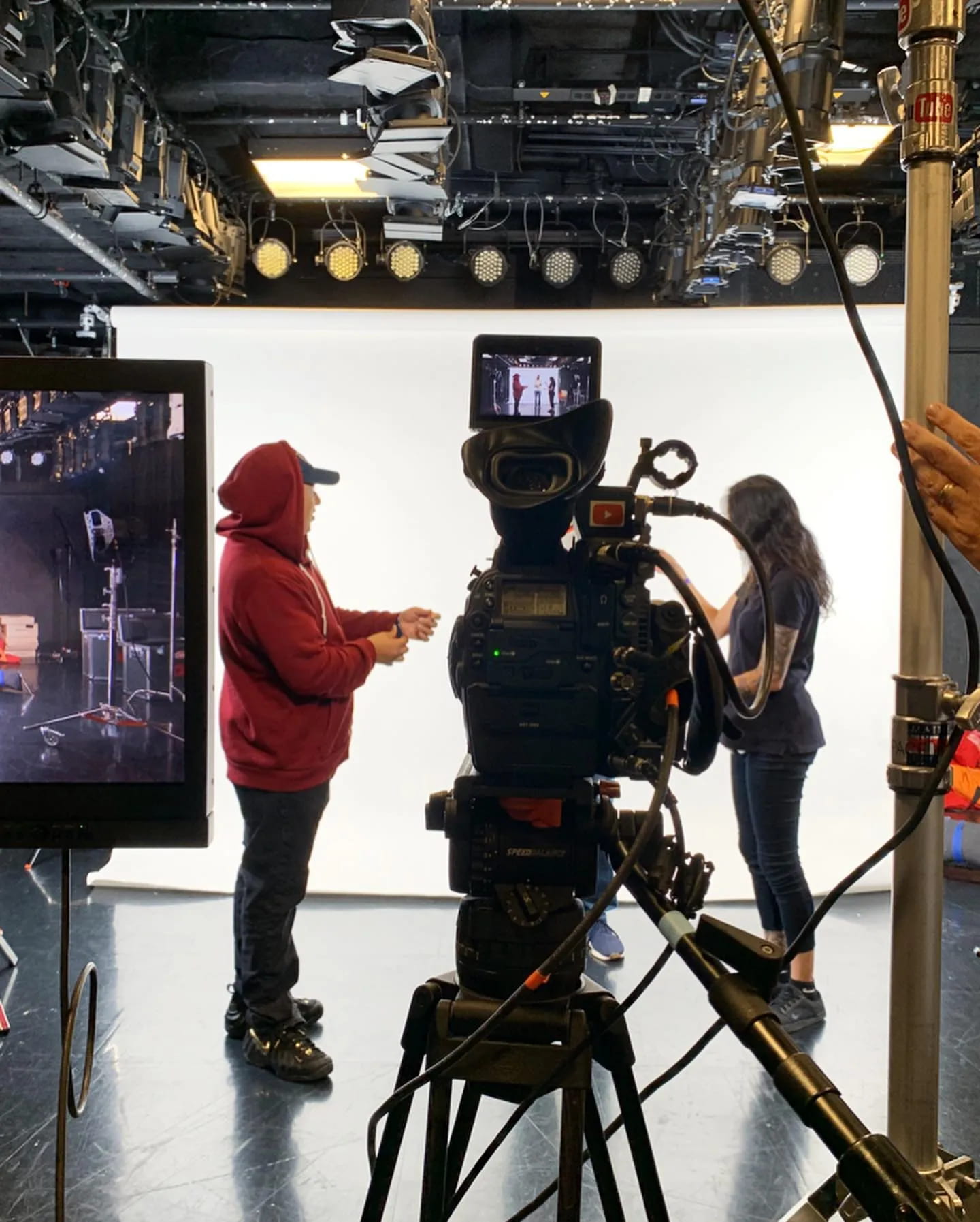 A cinema camera on set in front of a white studio backdrop.