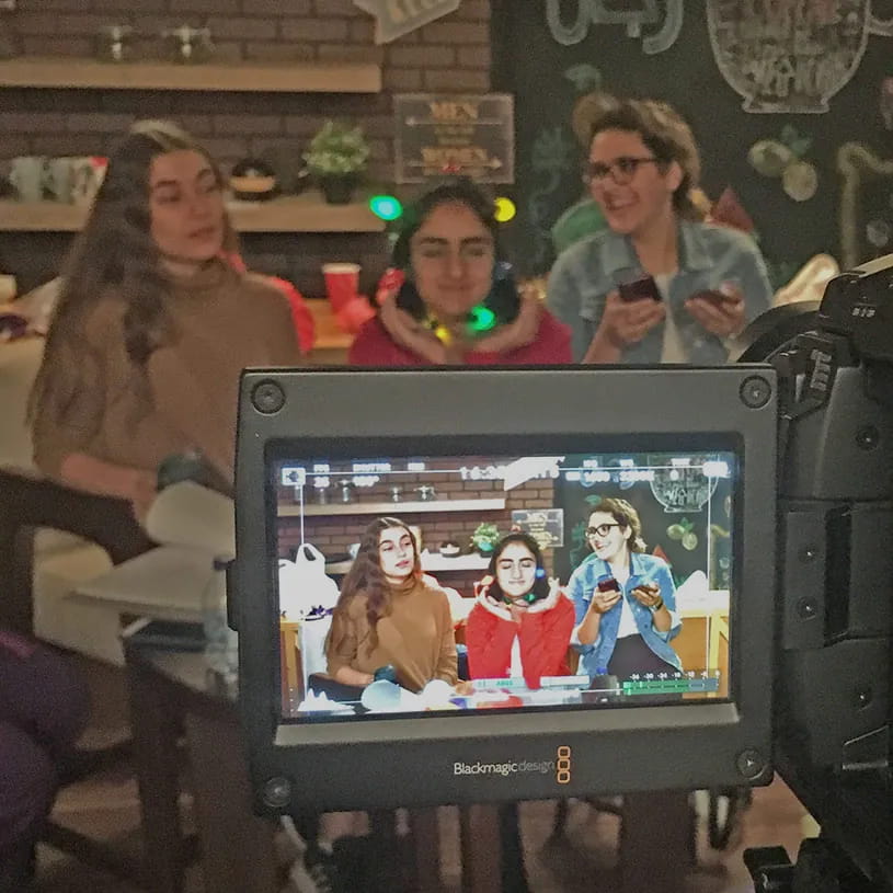 A camera monitor framing three people on a shoot.