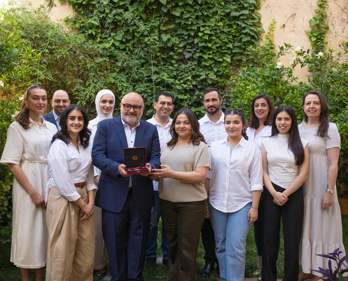 The Digitales team, about fifteen people, standing in front of an ivy-covered wall with their royal honour.